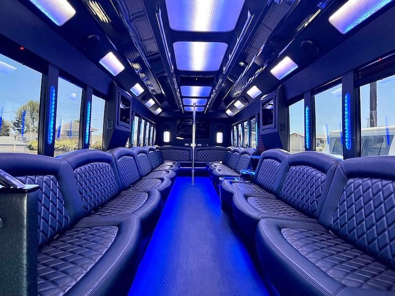 Empty party bus interior with blue LED lighting and leather bucket seating